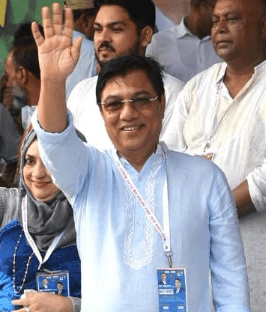 Millat smiling and waving among a group of people