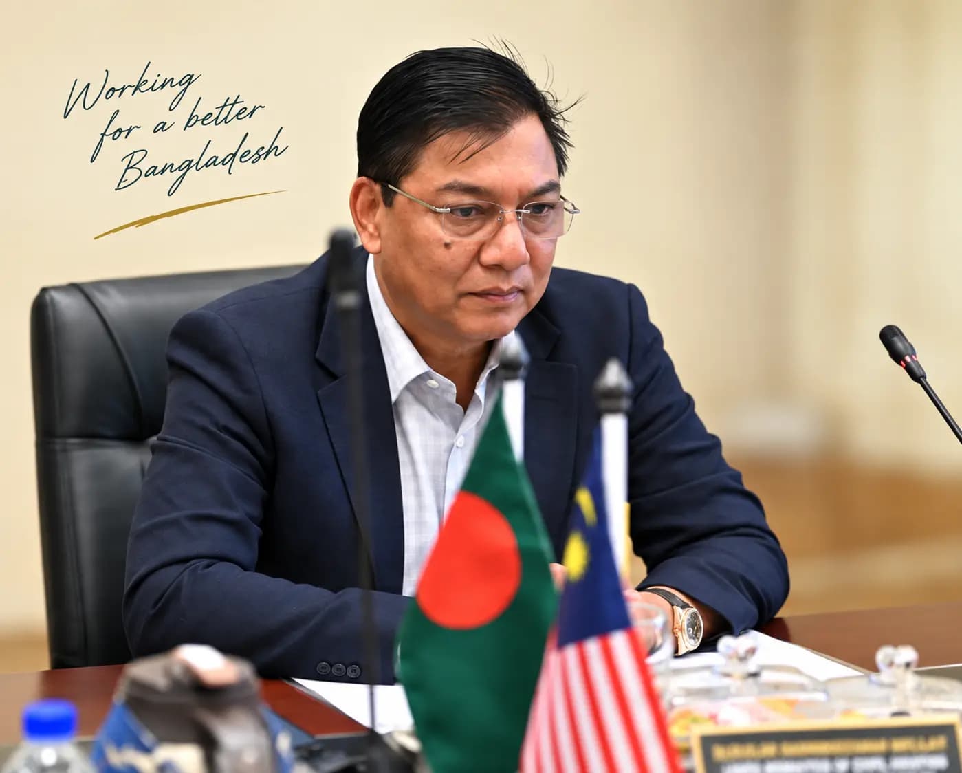 Reference-based image of M. Rashiduzzaman Millat seated with Bangladesh and Malaysia flags, with the words ‘Working for a better Bangladesh’