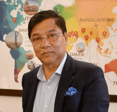 Millat seated in front of a tourism-themed backdrop